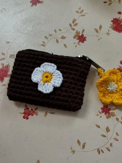 Our crochet wallet shown with a matching flower charm. It's a cute, coordinated set for keeping your cards and small items organized.