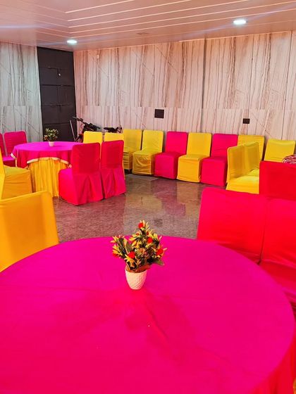 A simple and bright seating arrangement for a housewarming party or get-together. The use of vibrant pink and yellow fabric for the chairs and tables instantly makes the space feel festive.