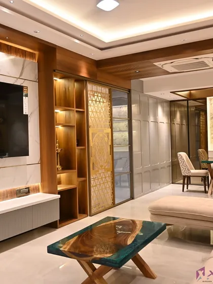 This is a glimpse into a complete living and dining space we designed. It features a cohesive theme with a marble-clad TV wall, a custom wooden bookshelf with a sliding jali door, and a dining area that feels both luxurious and connected to the living space.