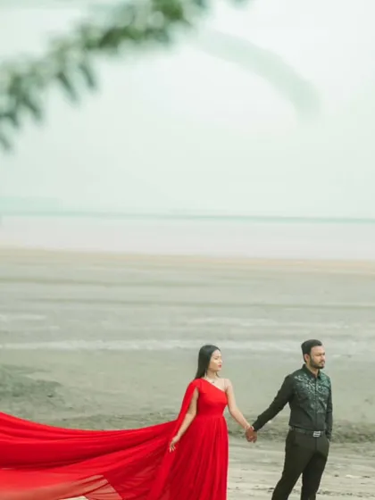 A minimalist composition where the red gown provides a slash of color against the pale sand and sky. This is a great choice for an artistic and modern pre-wedding photo.