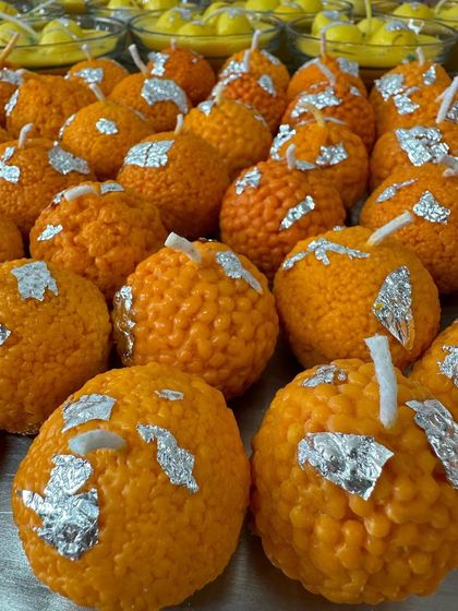 Laddoos everywhere! A close-up shot of dozens of freshly made laddoo candles, showing the detailed texture and hand-applied silver vark before they are packaged.