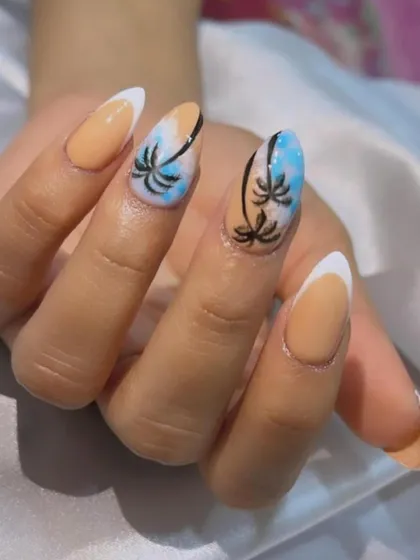 Get ready for your vacation with these Goa-themed nails. This design features a nude and blue sky ombré with hand-painted palm trees and a classic white French tip.