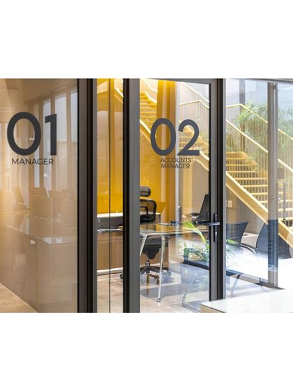 Clear and simple wayfinding is key in office design. The use of bold, minimalist graphics on glass partitions for the Manager and Accounts Manager cabins ensures clarity while maintaining an open feel.