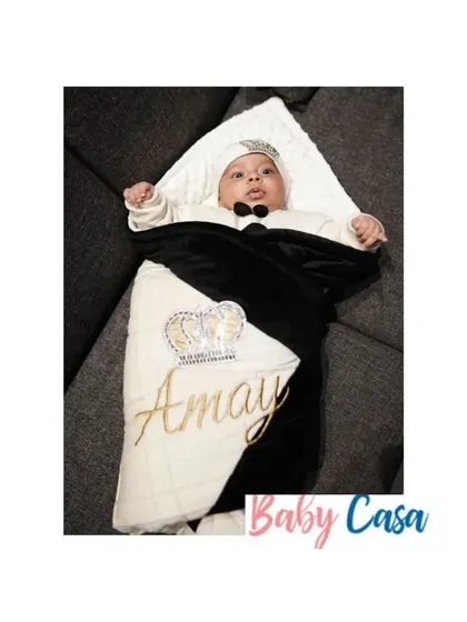 A full view of the personalized "Amay" wrap. The combination of black velvet and quilted white fabric, finished with a gold embroidered name and crown, creates a truly luxurious feel.
