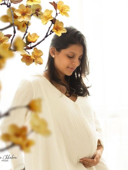 A touch of nature indoors. Using floral elements as a foreground frame adds depth and an artistic touch to this serene solo maternity portrait.