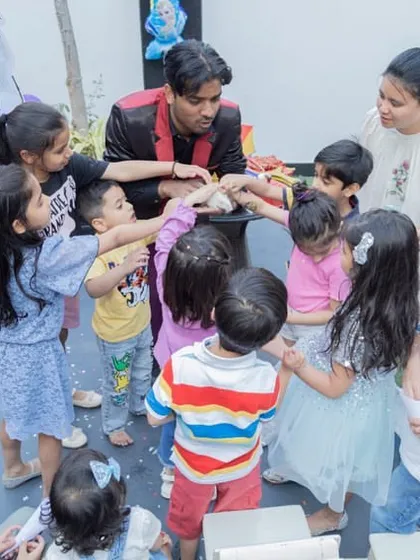 Even the magic show gets a themed touch! Here, kids are gathered around the magician, completely captivated by the fun and games at the Frozen party.