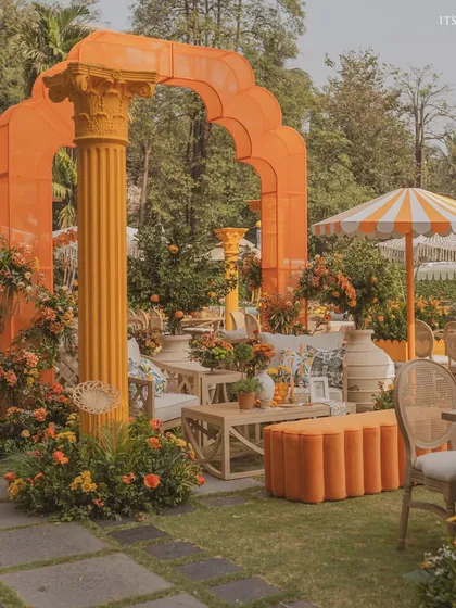 A wide view of the 'Orange Orchard' Haldi, where we used bold orange architectural elements, cane furniture, and lush greenery to create a vibrant atmosphere.