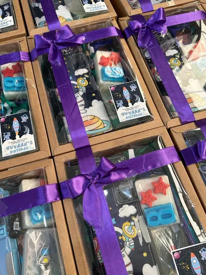 A space-themed birthday favor box, complete with custom soaps, a pencil case, a highlighter, and treats.