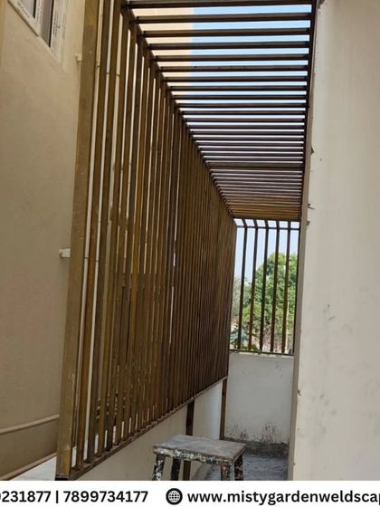 This safety grill with a built-in pergola-style roof provides both security and shade for a long balcony. The vertical bars ensure safety, while the overhead structure offers protection from the sun.