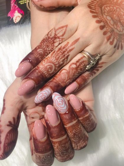 Here you can see how the hand-painted rose nail art ties in with the floral motifs in her henna. It's all about creating a cohesive and beautiful bridal look.