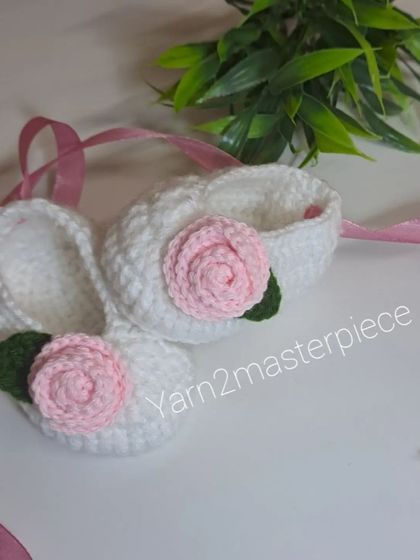 Simple and classic, these white booties are decorated with a single pink rose and tied with a matching pink ribbon.