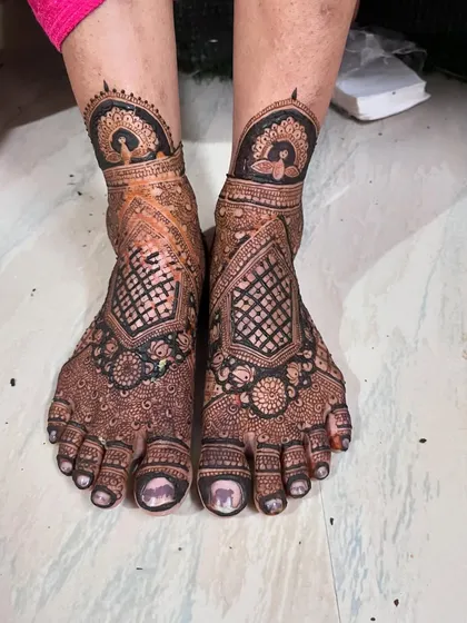 A unique feet design with a peacock anklet and a geometric pattern covering the foot. It's a modern take on traditional bridal mehendi.