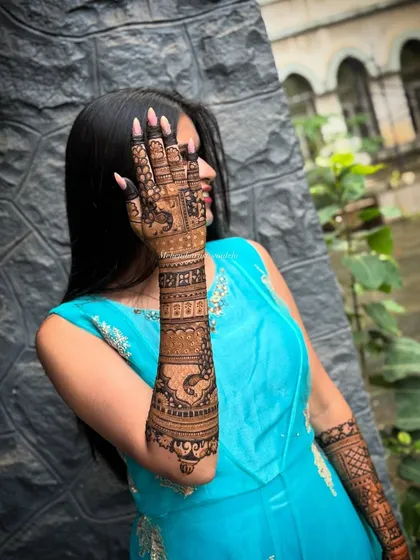 Nothing makes me happier than seeing a client thrilled with her mehendi. This is an engagement bride showing off her full-arm henna, featuring beautiful peacock motifs and detailed patterns.