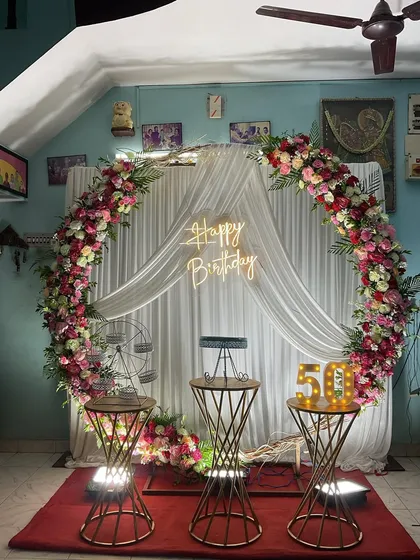 Celebrating a major milestone like a 50th birthday calls for an elegant touch. Here, I designed a beautiful circular backdrop framed with a lush garland of fresh flowers, complemented by a custom neon sign and large, illuminated numbers to mark the special occasion.