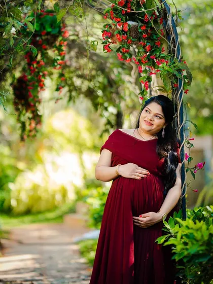 A solo maternity portrait in a garden pathway, capturing a moment of quiet reflection.