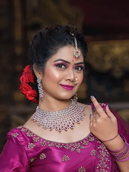 A smiling portrait in the magenta lehenga.