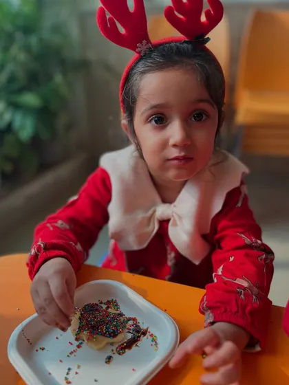 A little reindeer for the day! This student, wearing a festive headband, enjoys her sweet creation.