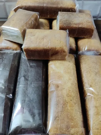 A large stack of wrapped loaf cakes, showing both my classic Mawa and rich Chocolate varieties ready for delivery.