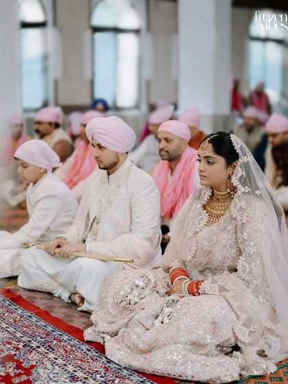 A serene moment from a Sikh wedding ceremony, or Anand Karaj. The soft color palette and the couple's calm demeanor reflect the peaceful and spiritual nature of the vows.