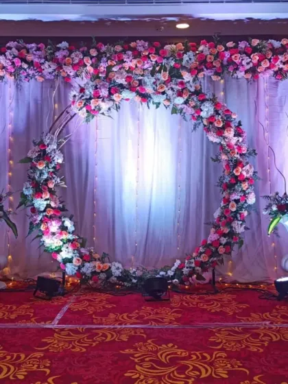 A stunning circular floral arch filled with pink, peach, and white roses. This makes for a beautiful and romantic photo booth or stage backdrop for a reception.