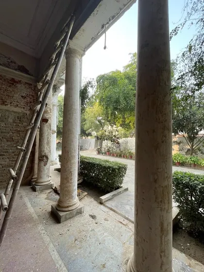 The process begins. The grand colonial-style columns of the portico are prepared for restoration, with the original brickwork exposed.