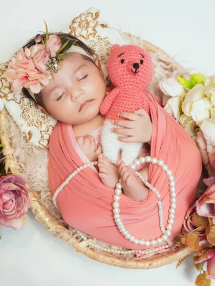 A sweet newborn girl surrounded by soft pink flowers and pearls. I love styling sessions with colors and props that complement your baby's gentle nature.