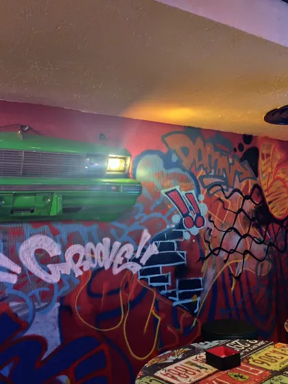 A different section of the cafe mural, showing how the graffiti style integrates with other elements like the front of a car mounted on the wall. It's all about creating a total vibe shift.