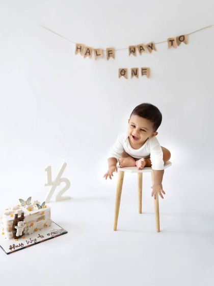 A playful moment from the half-birthday session, with the baby happily perched on a small stool.