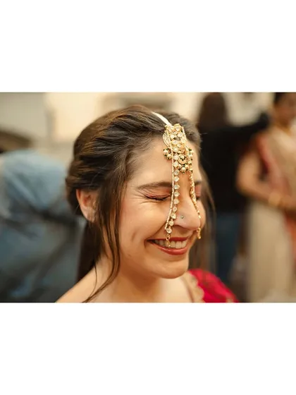 The bride, Amanda, beaming with a beautiful, natural smile as she gets her hair and makeup done for her Indian wedding.