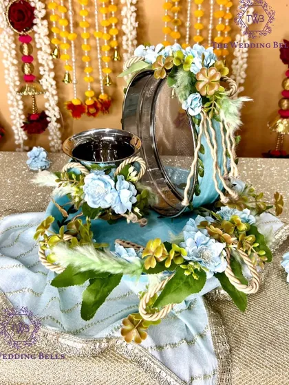 A beautiful pastel blue Karvachauth thali set from our 'Chaand' collection. Adorned with matching blue and gold flowers and rope detailing, this set offers a unique and serene color palette for your puja.