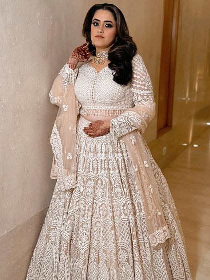 A full-length shot of the client, her ivory lehenga and bold makeup creating a stunning contrast.