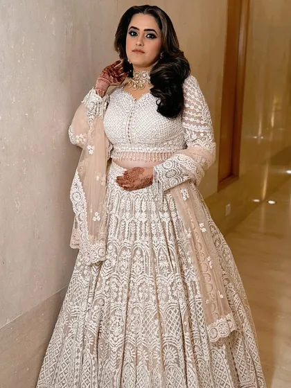 A full-length shot of the client, her ivory lehenga and bold makeup creating a stunning contrast.