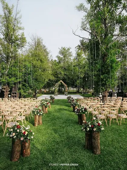 The stunning outdoor setup for Ameera and Richard's wedding, with wooden chairs and floral arrangements on log stumps. The rustic elegance is beautifully captured.