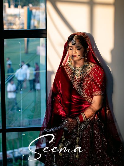 A serene bridal portrait by the window. The natural light and shadows create a beautiful, contemplative mood, highlighting the bride's elegance.