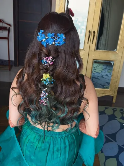 A punch of color for this Mehendi look. I used multi-colored floral accessories on her half-up hairstyle, which also features a pop of blue at the ends for a unique touch.