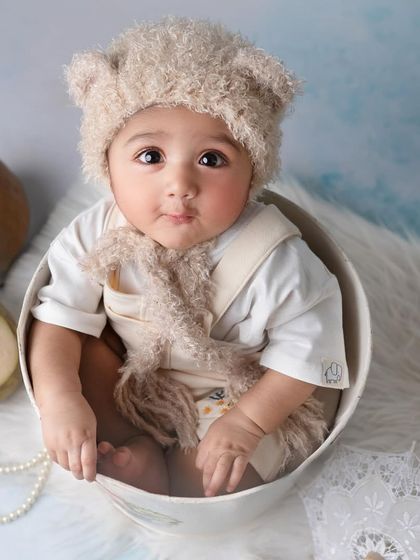A close-up of this adorable little one in a fuzzy hat. The soft textures and the baby's wide-eyed look make this a truly heartwarming portrait.