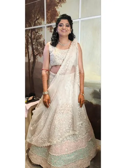 This bride's reception look is all about soft elegance. Her naturally curly hair is styled in a beautiful half-updo with a delicate accessory, and the makeup is kept soft and luminous.