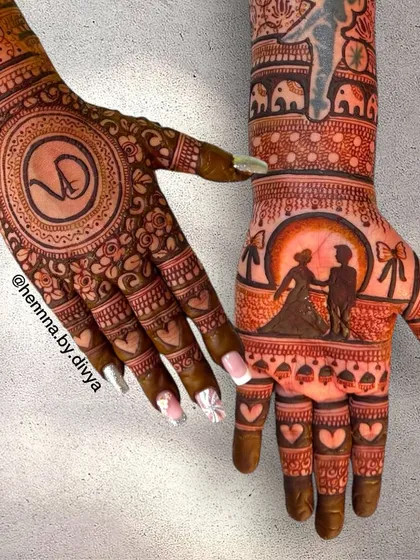This engagement mehendi tells a story across two hands. One hand features a romantic couple silhouette against a full moon, while the other has the couple's monogram 'VD' inside a detailed mandala.
