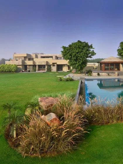A wide view of the C Farm property, showing the main house, the expansive lawn, and the poolside pavilion. The architecture is designed to sit comfortably in the landscape, creating a sprawling and luxurious farmhouse experience.