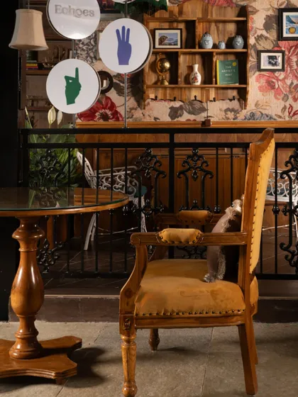 A detail of the eclectic decor at Echoes. The mustard-yellow armchair with its ornate wooden frame adds a pop of color and vintage flair, contributing to the café's warm and welcoming "living room" feel.