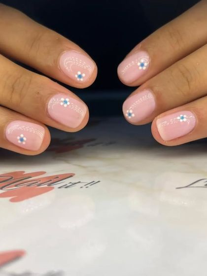 A delicate and sweet manicure with a sheer pink base and tiny, hand-painted white and blue flowers.