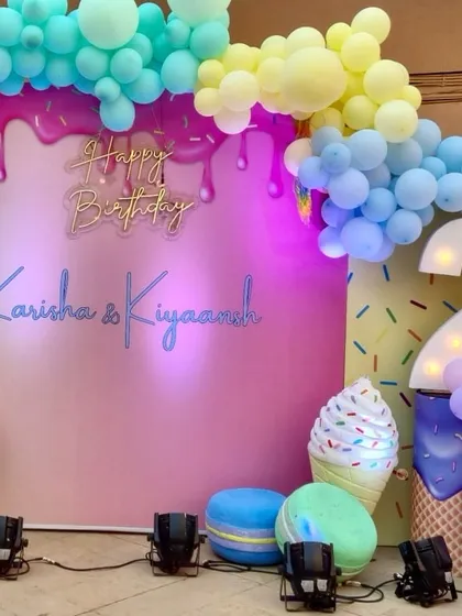 A candy-coated dream for a second birthday. The main backdrop features a 'Happy Birthday' sign, a large marquee number '2', and giant props of ice cream cones and macarons.