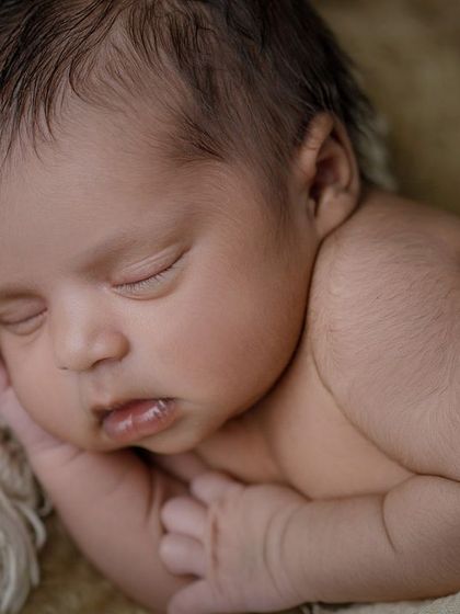 A close-up on pure peace. This photo focuses on the baby's delicate, sleeping face, nestled in soft, neutral-colored fabrics.
