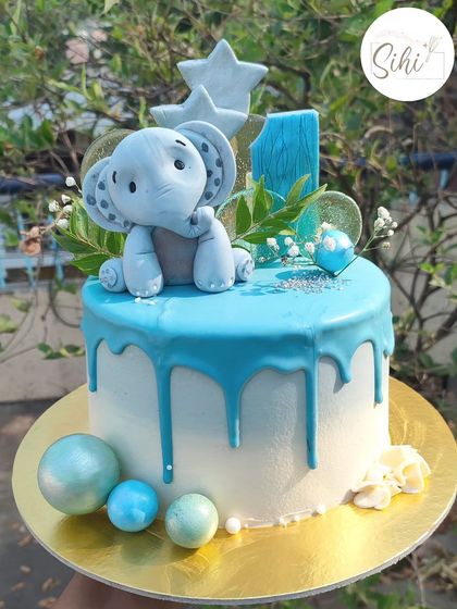 Anything with elephants is always cute. This first birthday cake has a blue ganache drip, an adorable fondant elephant topper, and fun isomalt lollipops for an extra touch of magic.