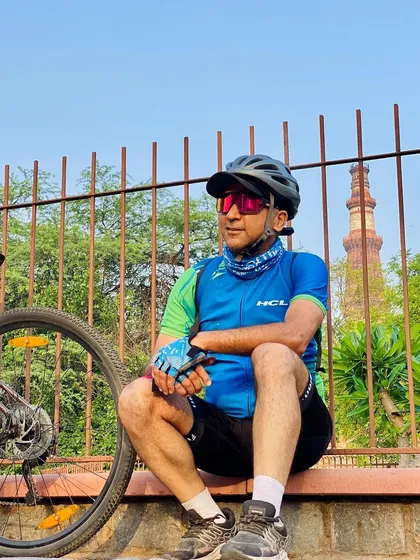 A cyclist taking a break with Qutub Minar in the background. Our rides are a tour of Delhi's rich history.