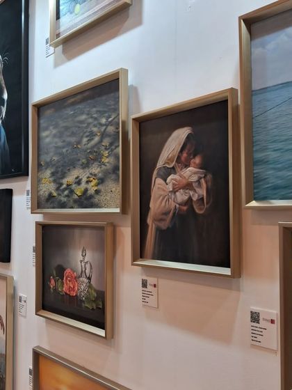 A section of Zeinab Sarkhosh's gallery wall, featuring a portrait of a mother and child alongside other realist works.