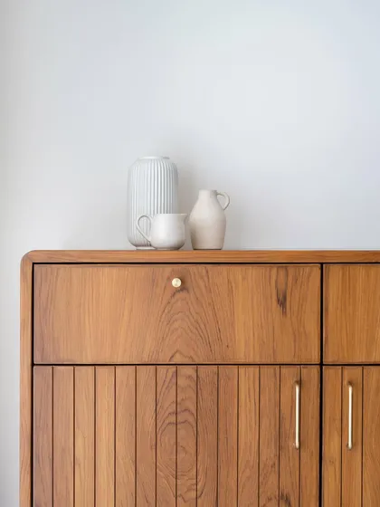 A detail shot of a custom wooden cabinet, showcasing the clean lines, fine grain, and subtle brass hardware.