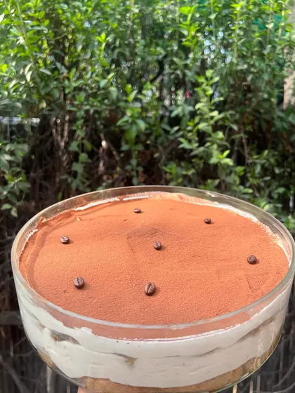 Our family-sized Tiramisu, ready for a party. This classic Italian dessert is made with coffee-soaked ladyfingers and a light, airy mascarpone cream.