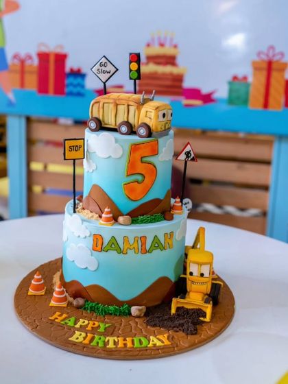A detailed shot of the two-tier cake, complete with edible dirt, traffic cones, and the cartoon vehicle characters.