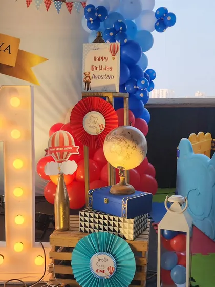 A close-up of the prop corner, featuring a large light-up number '1', a vintage-style globe, and other travel-themed elements that tie into the hot air balloon adventure concept.